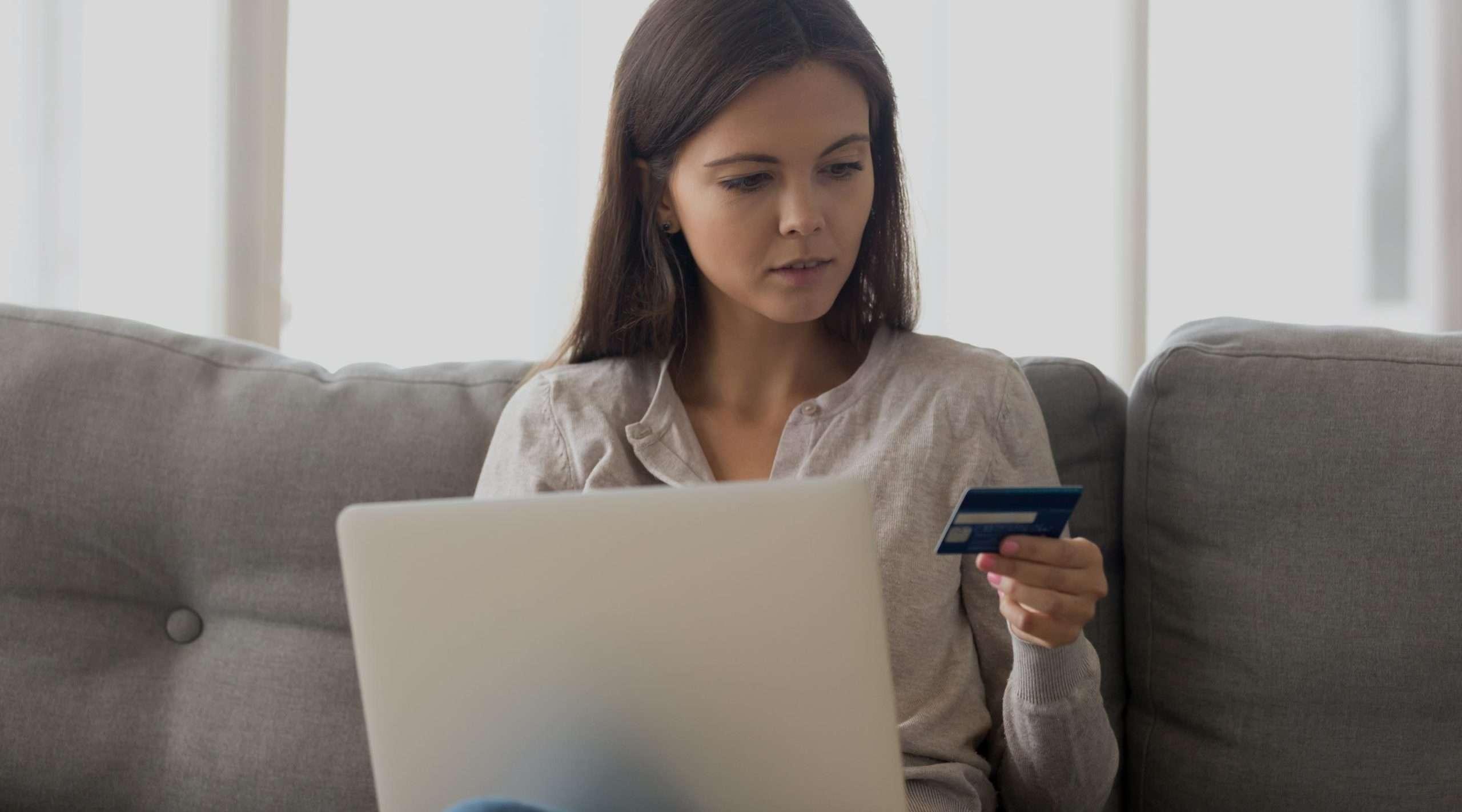 mujer preocupada mirando tarjeta de credito